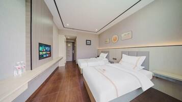 A hotel room with two beds, a TV on the wall, and a bathroom visible through an open door.