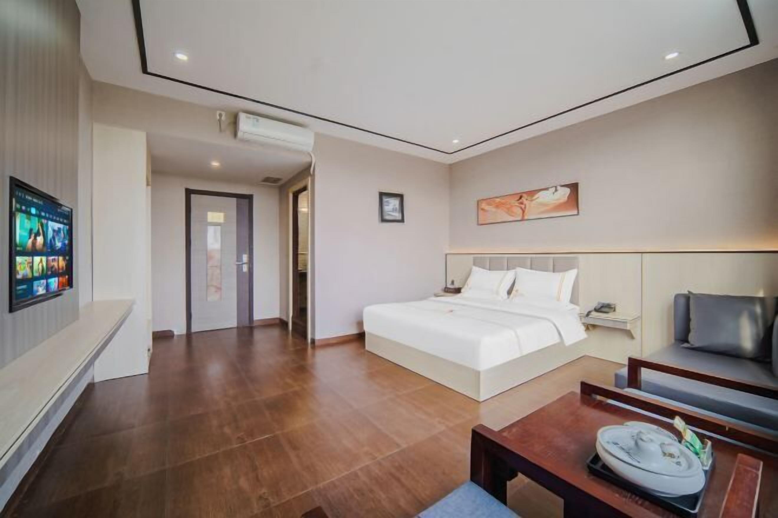 A modern hotel room with a large bed, a TV, a coffee table, and a sofa.