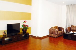 Una sala de estar con televisor de pantalla plana, un sofá de cuero marrón y una mesa de centro.