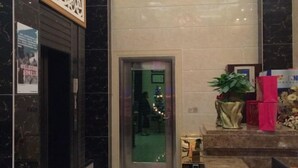 Un vestíbulo con piso de mármol, un mostrador de recepción, un árbol de Navidad y una pequeña estatua.