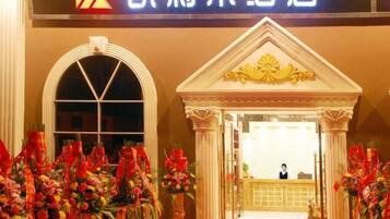 A hotel entrance with a reception desk, columns, and a sign above.
