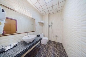 Un baño con lavamanos blanco, espejo, inodoro y ducha.