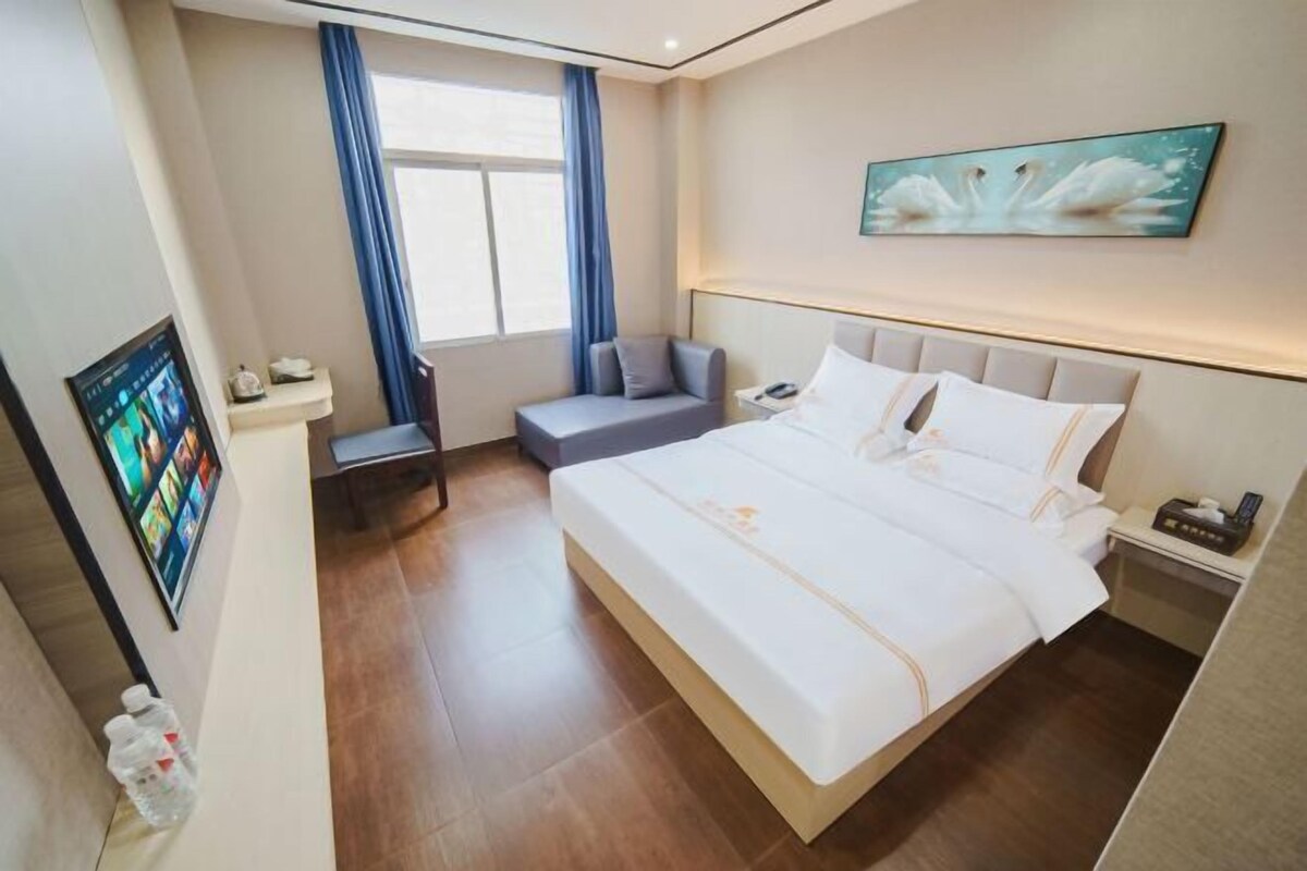 Habitación de hotel con una cama grande, un escritorio, una silla, un televisor y un cuadro en la pared.