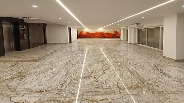 A spacious hallway with marble flooring, recessed lighting, and a large mural on the far wall. - Hotel Sheldon Inn (Kolkata)