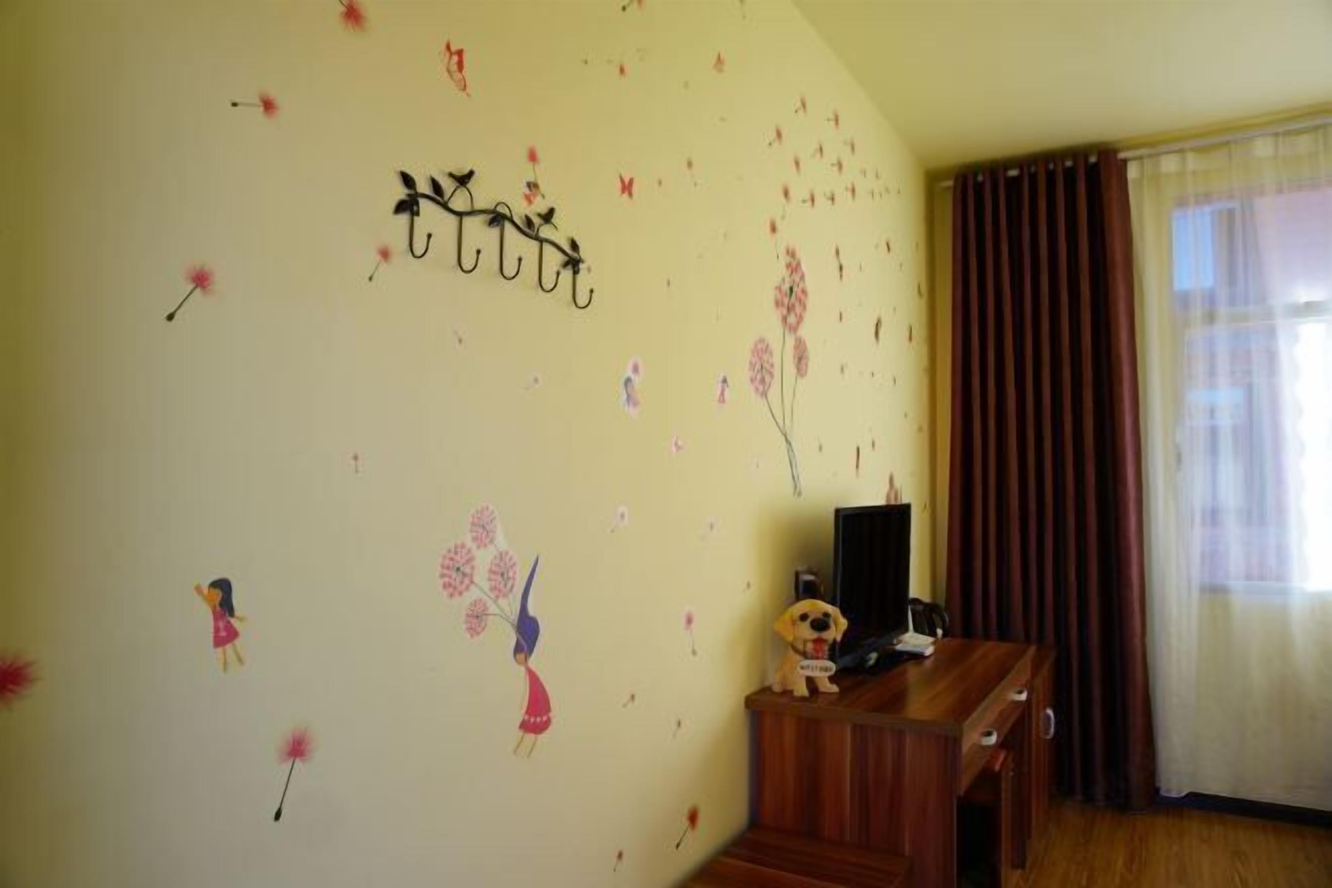 A room with a wooden desk, a television, and a wall decorated with floral stickers.