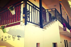 A building with a white facade, black railings, and potted plants on the balcony.