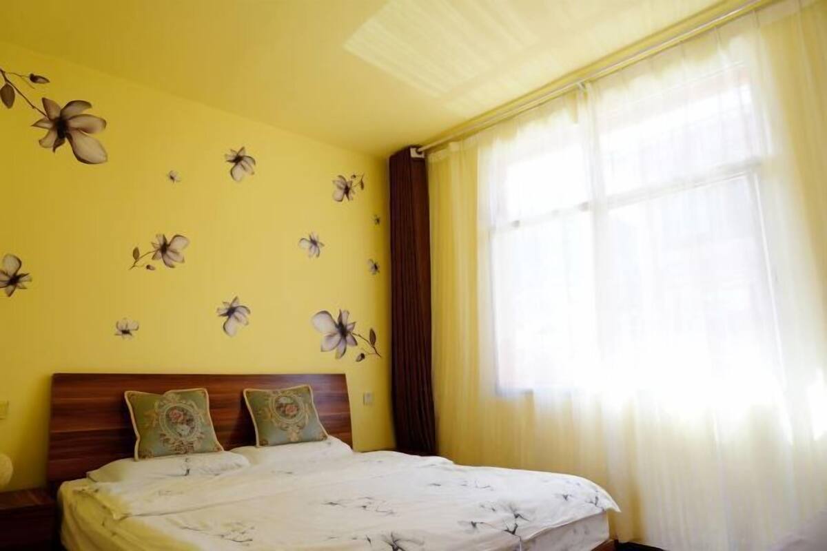 Une chambre à coucher avec un lit, une table de chevet et une fenêtre avec des rideaux.