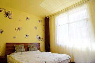 Um quarto com uma cama, uma mesa de cabeceira e uma janela com cortinas.