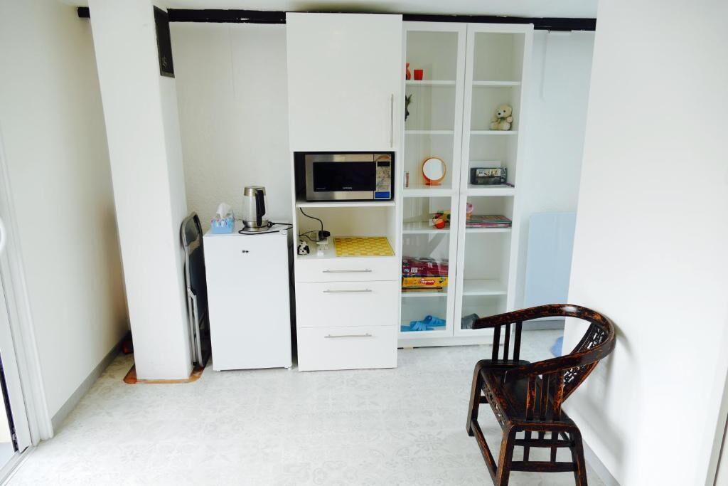 Una habitación compacta con un armario blanco, un escritorio pequeño con un ordenador y una silla de madera.