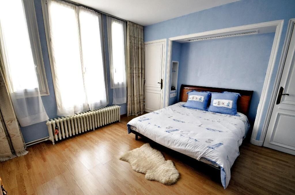 A bedroom with a bed, curtains, a radiator, and a wooden floor.