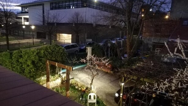 A nighttime view of a parking area with cars, a building in the background, and a wooden deck in the foreground. - Chalet de Paris (Fontenay-sous-Bois)