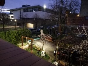 A nighttime view of a parking area with cars, a building in the background, and a wooden deck in the foreground. - Chalet de Paris (Fontenay-sous-Bois)