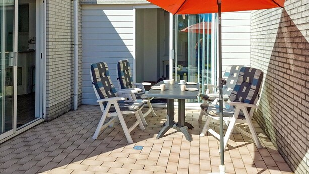 A patio with a table and chairs, an umbrella, and a brick wall. - Gorgeous home in Callantsoog with WiFi (Callantsoog)