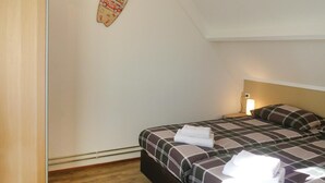 Ein Schlafzimmer mit einem Bett, Kissen, einem Nachttisch mit Lampe und einer Wanddekoration.