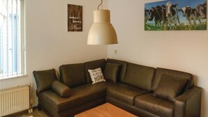 Ein Wohnzimmer mit braunem Ledersofa, einem Holztisch, einer Pendelleuchte und zwei Wandbildern.