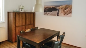 Ein Essbereich mit Holztisch und -stühlen, einer Kommode und einem Bild einer Strandansicht an der Wand.
