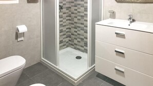 Un baño moderno con ducha, inodoro y lavamanos.