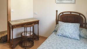 Un dormitorio con una cama de madera, un escritorio pequeño de madera y una silla.