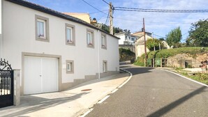 Una calle residencial tranquila con un edificio blanco, varios ventanales y un portón de garaje.