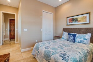 Un dormitorio con cama, una puerta, un cuadro enmarcado en la pared y una silla de mimbre.