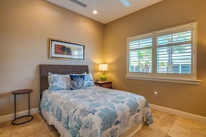 A bedroom with a bed, a nightstand, a lamp, a framed picture on the wall, and a window with blinds.
