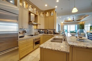 A modern kitchen with stainless steel appliances, beige cabinetry, granite countertops, and pendant lighting. - The View at Bradenton Beach Club (Bradenton Beach)
