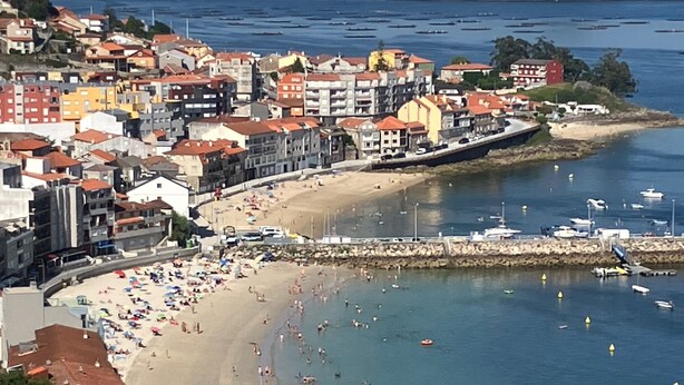 Un pueblo costero con playa, edificios y barcos.