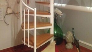 Una escalera de caracol con escalones de madera y barandillas blancas, que conduce a un piso superior.