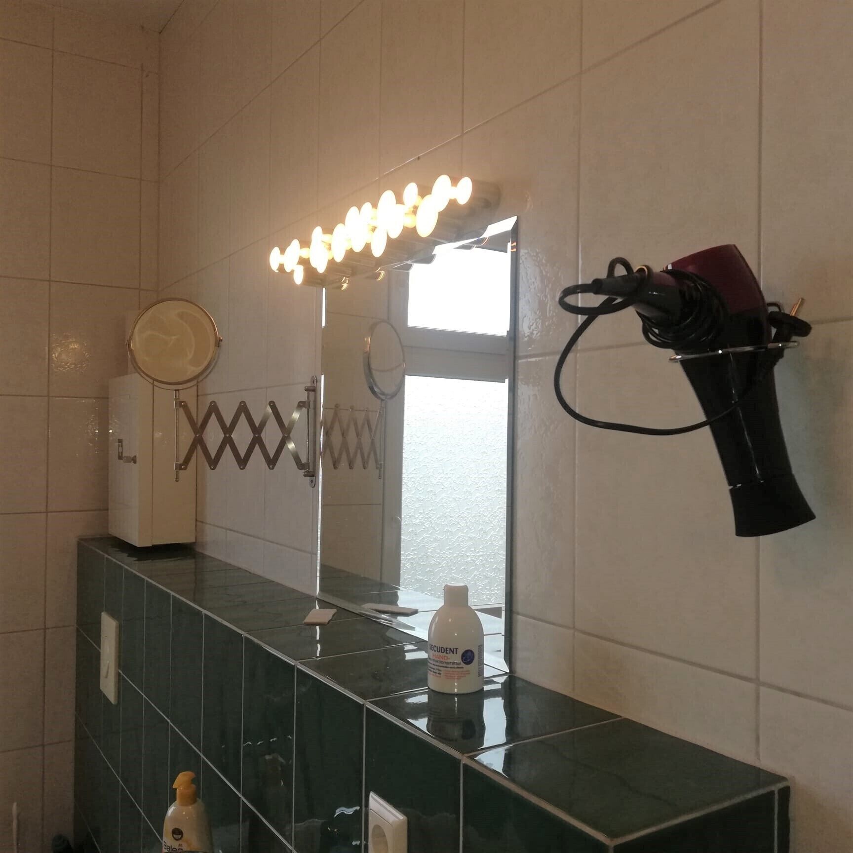 Een badkamer met een wastafel, een spiegel en verlichting boven de wastafel.