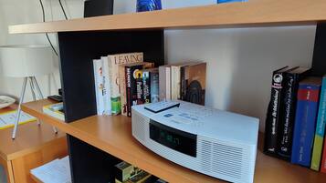 Ein Bücherregal mit verschiedenen Büchern, einer digitalen Uhr und einem Fernseher.