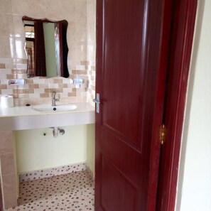 A bathroom with a sink, mirror, and tiled floor.