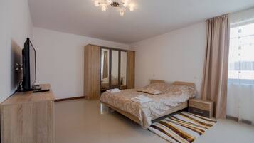 Une chambre à coucher comprenant un lit, des tables de chevet, une armoire, un téléviseur et un luminaire au plafond.