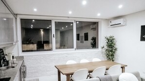 A modern kitchen with a dining area, large windows, and a potted plant.