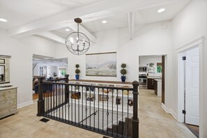 A spacious interior with a staircase, a chandelier, a kitchen, and a dining area. - The Nest: Epic Family Home w/ Rock Climbing+Slide (Chattanooga)