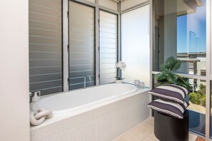 A modern bathroom with a large bathtub, a glass shower enclosure, and a view of the outside. - 1 Bright Point Apartment 1307 (Nelly Bay)