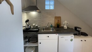 Una cocina compacta con estufa, lavamanos y gabinetes blancos.