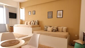 Una sala moderna con un conjunto de sofás, un televisor montado en la pared y obras de arte enmarcadas.