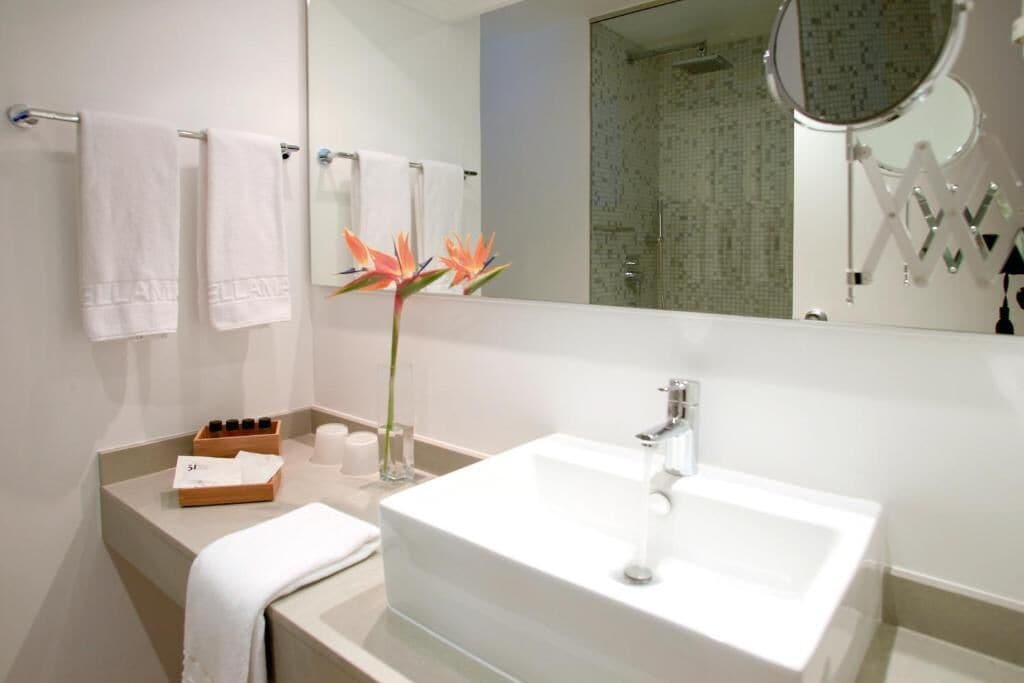 Een moderne badkamer met een grote witte wastafel, een spiegel en een douchehoek.