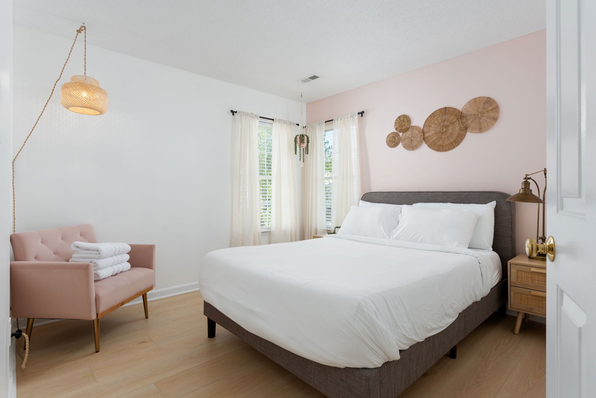 A bedroom with a bed, a chair, a nightstand, and a hanging light fixture.