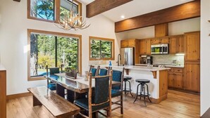 Une cuisine spacieuse dotée de meubles en bois, d’un îlot central et d’un coin repas avec une banquette et des chaises.