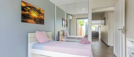 Un dormitorio con una cama, un espejo grande y un cuadro en la pared.