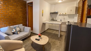 A compact living space with a sofa, a coffee table, a kitchen area with a stove, cabinets, and a refrigerator. - Tupac Hostel Huaraz (Huaraz)