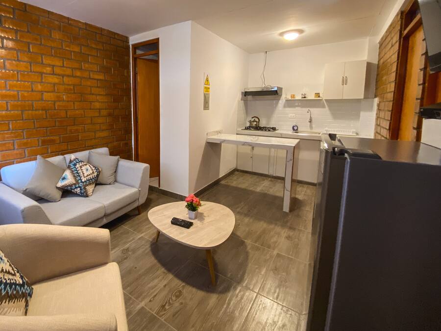 Un espacio habitable compacto con sofá, una mesa de centro, una zona de cocina con estufa, armarios y refrigerador.