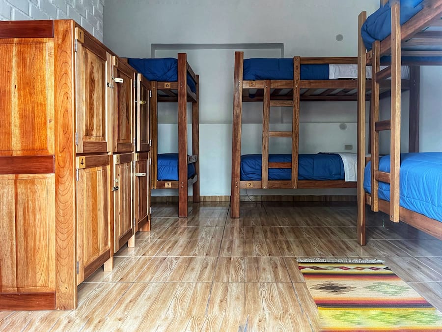 A dormitory room with bunk beds, wooden cabinets, and a patterned rug.