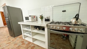 A kitchen with a stove, microwave, and refrigerator. - Tupac Hostel Huaraz (Huaraz)