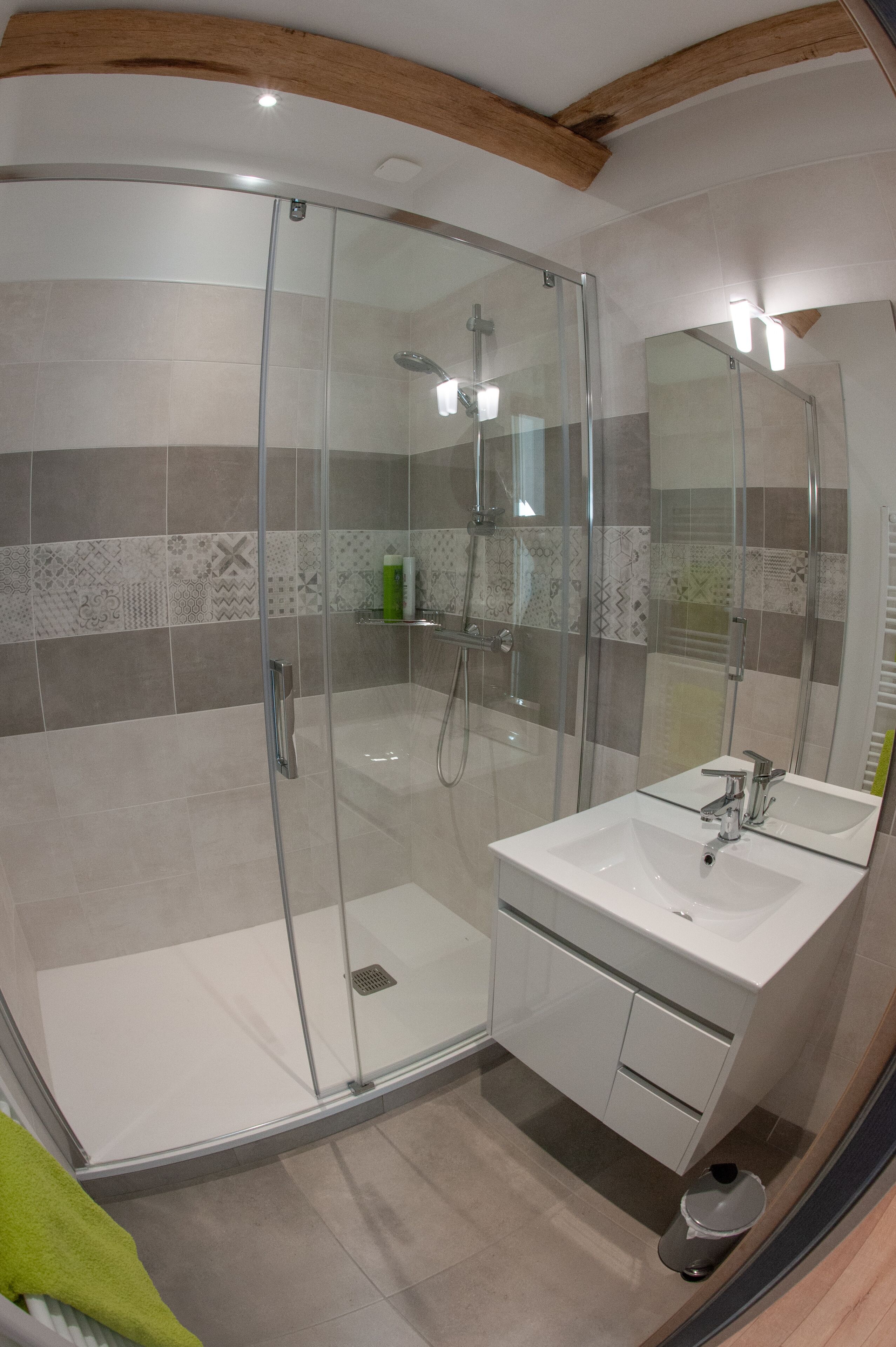 A modern bathroom with a glass-enclosed shower, a white sink, and a mirror.