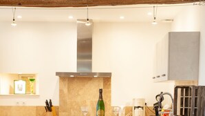 Une cuisine avec deux tabourets de bar, une bouteille de vin et une machine à café.