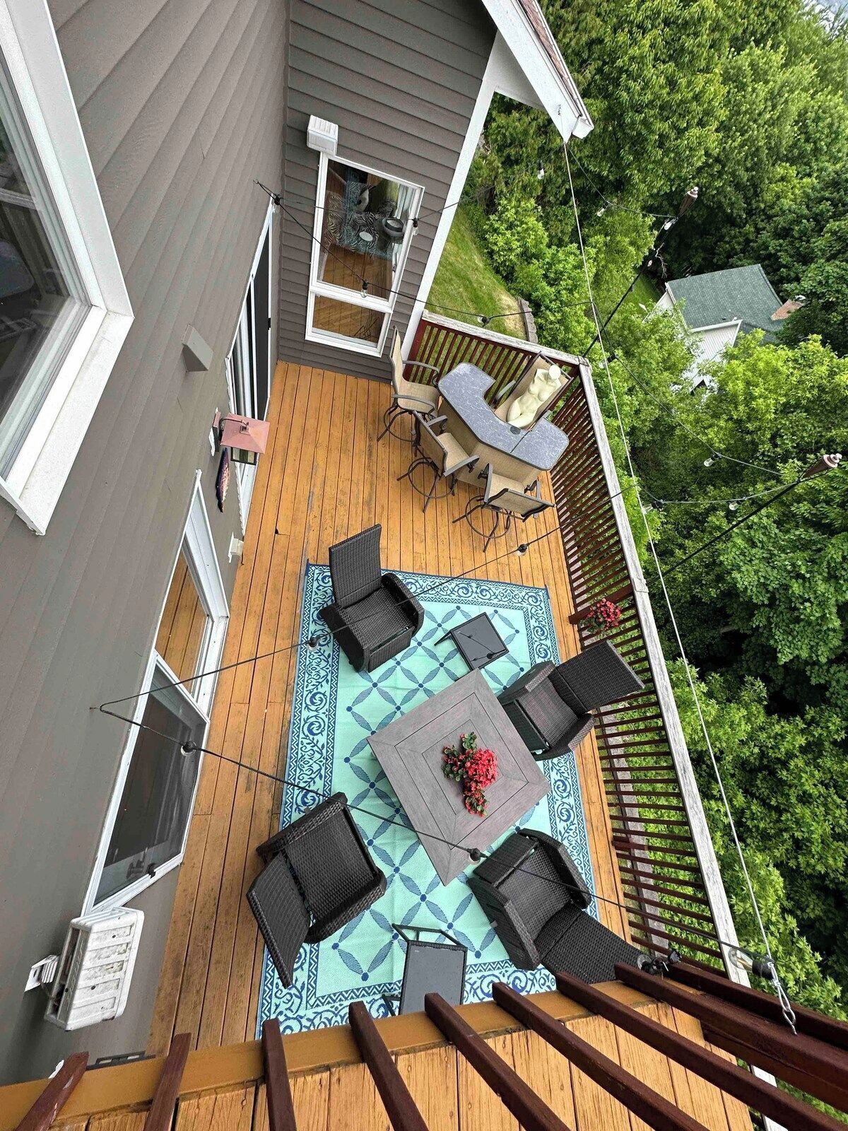 Eine Terrasse mit Tisch und Stühlen, umgeben von einem Holzdeck und einem gemusterten Teppich.