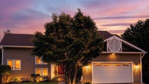 A two-story house with a garage, a tree in the front yard, and a driveway. - Open layout with views, jacuzzi tub (Syracuse)