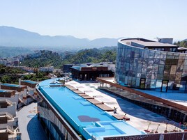 Una piscina en la azotea con vistas despejadas al paisaje urbano circundante y montañas.